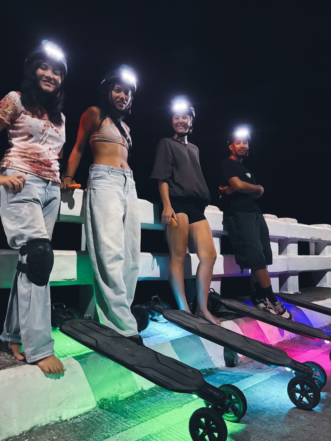 Riders lined up with glowing electric skateboards on the Catangnan Bridge at night