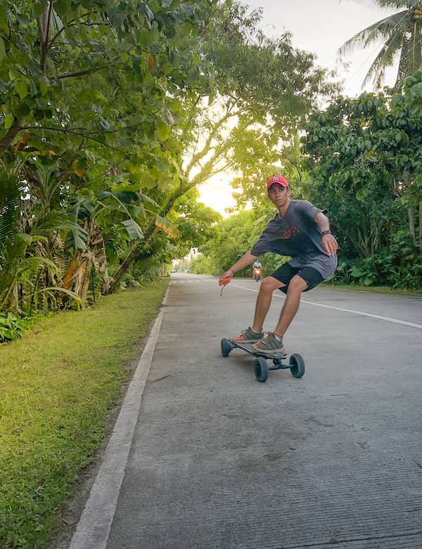 Matt, eSkate guide, riding an electric skateboard on the coastal road in Siargao